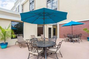 a patio with tables and chairs with blue umbrellas at Hampton Inn Norcross in Norcross