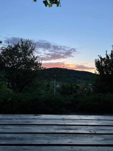 um pôr-do-sol sobre uma colina com árvores e um campo em Woźniówka pod Mogielicą em Słopnice