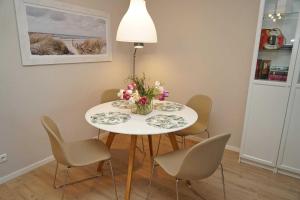 a white table with chairs and a vase of flowers on it at Ferienwohnung zur Hafenseite _ 200 in Damp