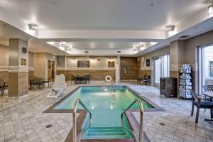 Homewood Suites by Hilton Boston Brookline-Longwood Medical في بروكلاين: مسبح في وسط غرفة مع طاولات وكراسي