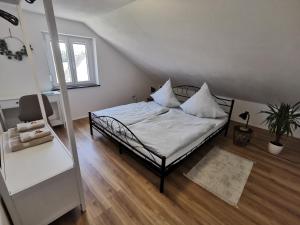 una camera da letto con letto, lenzuola e cuscini bianchi di Ferienwohnung Rein a Oberteuringen