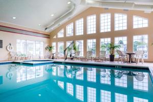 an indoor pool with a table and chairs and windows at Hampton Inn & Suites Chincoteague-Waterfront, Va in Chincoteague