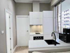 a kitchen with white cabinets and a sink at COQUETO APARTAMENTO in Torrelavega