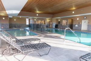 a swimming pool with two chairs in a building at Hilton Garden Inn West Des Moines in West Des Moines