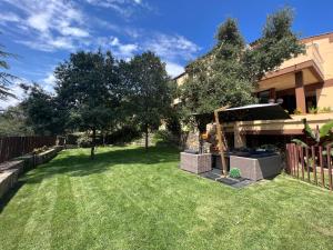 einen Hof mit einem Zaun und einigen Bäumen und Gras in der Unterkunft Les Alzines - Chalet con gran piscina cerca de Barcelona in Orrius