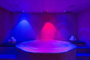 bañera de hidromasaje en una habitación con luces moradas y azules en Hotel Màgic Andorra, en Andorra la Vella