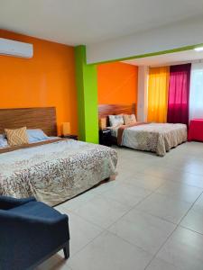 - 2 lits dans une chambre aux murs colorés dans l'établissement Hotel boutique CVC, à Acapulco