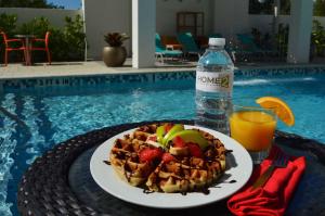 a plate of waffles and fruit on a table next to a pool at Home2 Suites By Hilton Ft. Lauderdale Airport-Cruise Port in Dania Beach