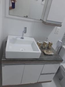 uma casa de banho com um lavatório branco e um espelho. em Aconchego Lagoinha Casa Frente em Florianópolis