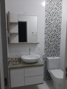 a bathroom with a sink and a toilet and a mirror at Aconchego Lagoinha Casa Frente in Florianópolis