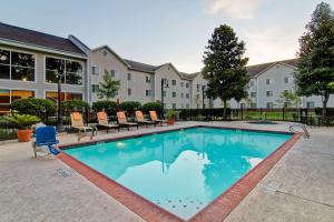 a swimming pool with chairs and a building at Homewood Suites Houston Kingwood Parc Airport Area in Kingwood