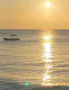 a boat in the ocean with the sun setting at suítes Pataxós in Cumuruxatiba