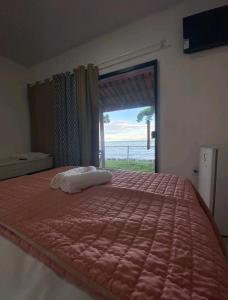 um quarto com uma cama grande e vista para o oceano em suítes Pataxós em Cumuruxatiba