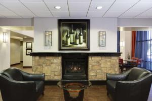 a lobby with a fireplace and two chairs and a painting at Hampton Inn & Suites Temecula in Temecula