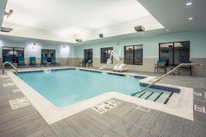 a swimming pool in a large room with chairs and tables at Hampton Inn & Suites Yonkers - Westchester in Yonkers