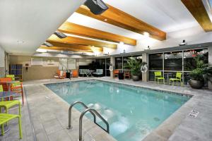 a large pool in a hotel with chairs and tables at Home2 Suites by Hilton Little Rock West in Little Rock