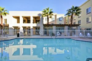 a swimming pool in front of a building with palm trees at Homewood Suites by Hilton Palm Desert in Palm Desert