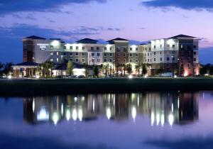 a large building with its reflection in the water at night at Homewood Suites Port Saint Lucie-Tradition in Port Saint Lucie