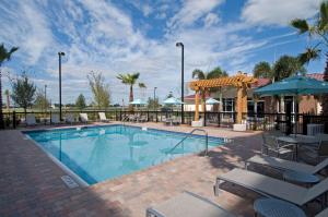 uma piscina num resort com cadeiras e guarda-sóis em Homewood Suites Port Saint Lucie-Tradition em Port Saint Lucie