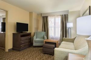 a hotel room with a couch and a tv and a chair at Homewood Suites by Hilton Princeton in Princeton