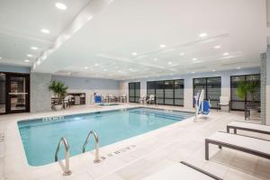 a pool in a hotel with tables and chairs at Hampton Inn Rochester Penfield, Ny in Penfield