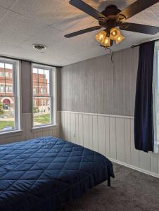 Schlafzimmer mit einem blauen Bett und einem Deckenventilator in der Unterkunft Charming Apartments in the Heart of Robinson in Robinson