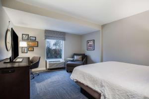 a hotel room with a bed and a desk and a chair at Hampton Inn Rochester Penfield, Ny in Penfield