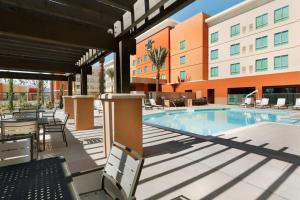 uma piscina num hotel com cadeiras e um edifício em Homewood Suites By Hilton Irvine John Wayne Airport em Irvine
