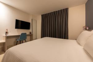 カルタヘナ・デ・インディアスにあるHOTEL RILUX CARTAGENAのベッド、デスク、テレビが備わるホテルルームです。