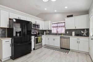 a large kitchen with black appliances and white cabinets at Eclectic Pool Ping-Pong Fire Pit 3 BR in Peoria