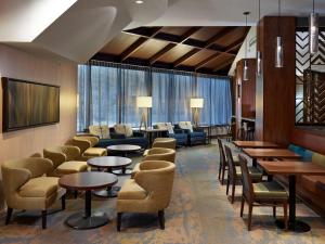 DoubleTree by Hilton Hotel & Conference Centre Regina في ريجينا: غرفة انتظار مع طاولات وكراسي ونوافذ