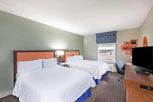 a hotel room with two beds and a flat screen tv at Hampton Inn Ozona in Ozona