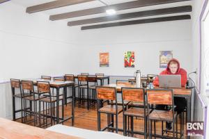 a woman sitting at a table with a laptop at Barcelona Hostel in Mar del Plata