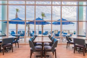 a restaurant with tables and chairs and blue umbrellas at Hampton Inn & Suites Panama City Beach-Beachfront in Panama City Beach