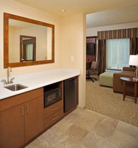 ein Hotelzimmer mit einem Waschbecken und einem Wohnzimmer in der Unterkunft Hampton Inn & Suites Pittsburgh Waterfront West Homestead in West Homestead