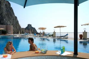 
people sitting at a table with umbrellas at Capo Dei Greci Taormina Coast Hotel & SPA in Santa Margherita-Sant'Alessio Siculo
