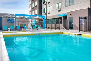 une grande piscine avec des chaises et des parasols bleus dans l'établissement Tru By Hilton St. George, à Saint George