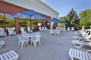 a patio with white tables and chairs and blue umbrellas at Hampton Inn Toledo-South/Maumee in Maumee