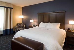 オタワにあるHampton Inn by Hilton Ottawa Airportの大きなベッドと椅子のあるホテルの部屋 +6枚の写真