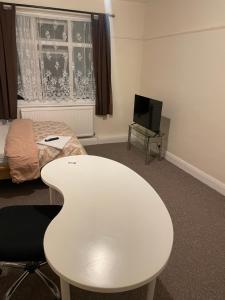 a room with a white table and a bed and a tv at Welcome to your new home. in Redbridge +5 photos