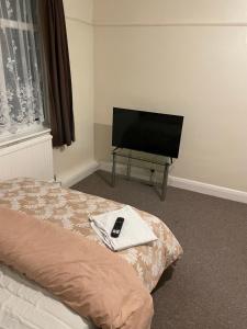 a bedroom with a tv and a bed with a remote at Welcome to your new home. in Redbridge