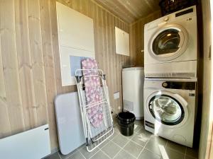 a kitchen with a washing machine and a washer at Sunset Panorama - Superior Cabin Lofoten in Sand