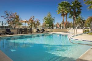 a swimming pool with chairs and a table and palm trees at Hampton Inn & Suites Suisun City Waterfront in Suisun City