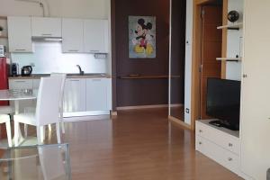 a kitchen with white cabinets and a table and a television at Suite chocolat in Cuneo +33 photos
