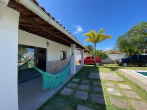 a hammock hanging from the side of a house at Casa Cantinho de Arembepe - Linda casa com piscina no litoral norte da Bahia in Camaçari