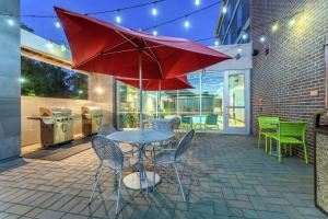 a patio with a table with chairs and a red umbrella at Home2 Suites Dover in Dover