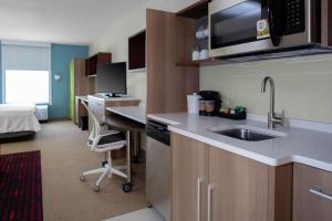 eine Küche mit einem Waschbecken und einem Schreibtisch in einem Zimmer in der Unterkunft Home2 Suites By Hilton Denver South Centennial Airport in Centennial