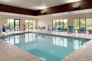 een groot zwembad met blauwe stoelen, tafels en ramen bij Hampton Inn West Des Moines Lake Drive in West Des Moines