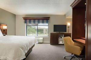 Habitación de hotel con cama, escritorio y TV. en Hampton Inn West Des Moines Lake Drive, en West Des Moines