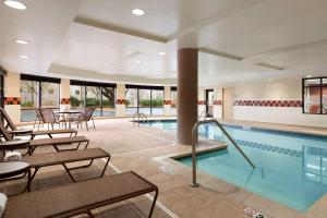 a swimming pool with tables and chairs in a building at Hampton Inn & Suites East Hartford in East Hartford